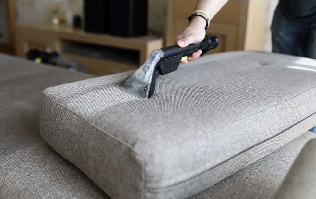 Upholstery cleaning of a sofa, revealing a streak of cleaner fabric where the cushion has been cleaned.